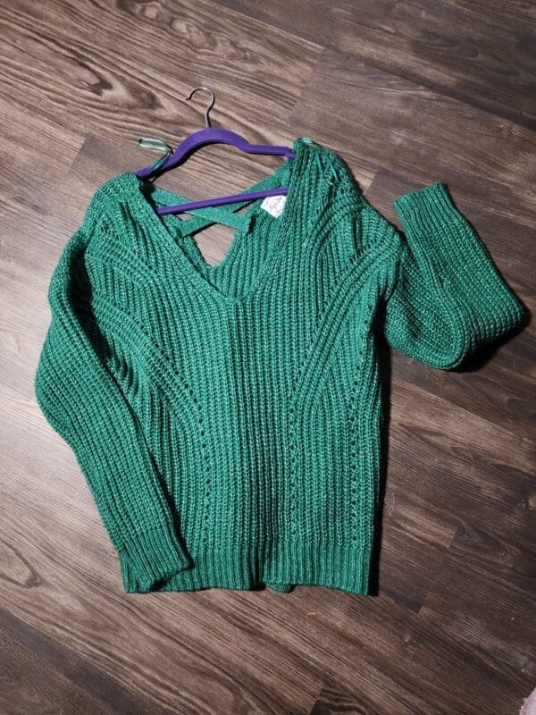 A green sweater hanging on the wall