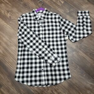 A black and white checkered shirt is laying on the floor.